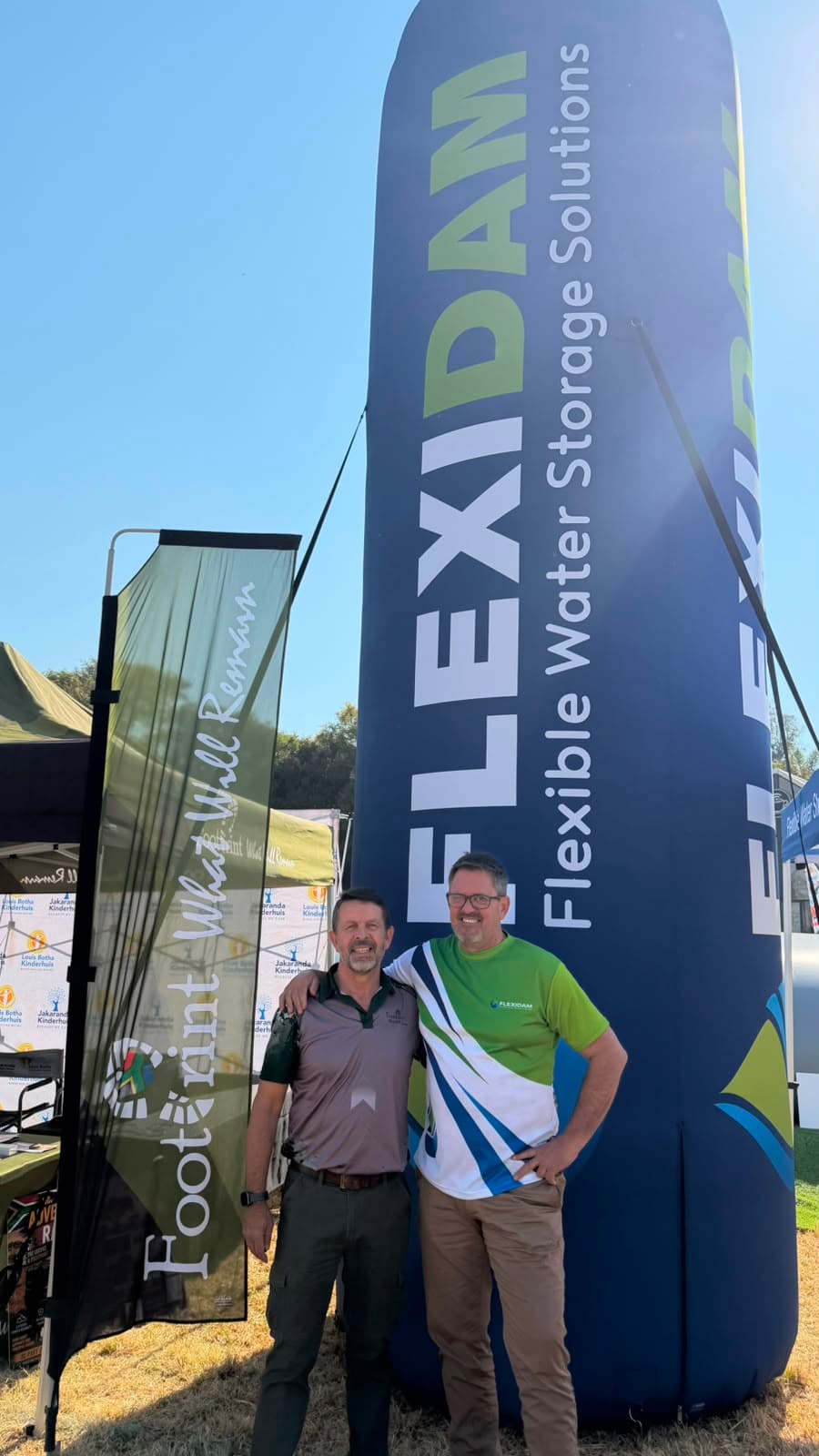 Two of the FlexiDam team beside the inflatable FlexiDam pillar and the Footprint banner at KragDag 2026