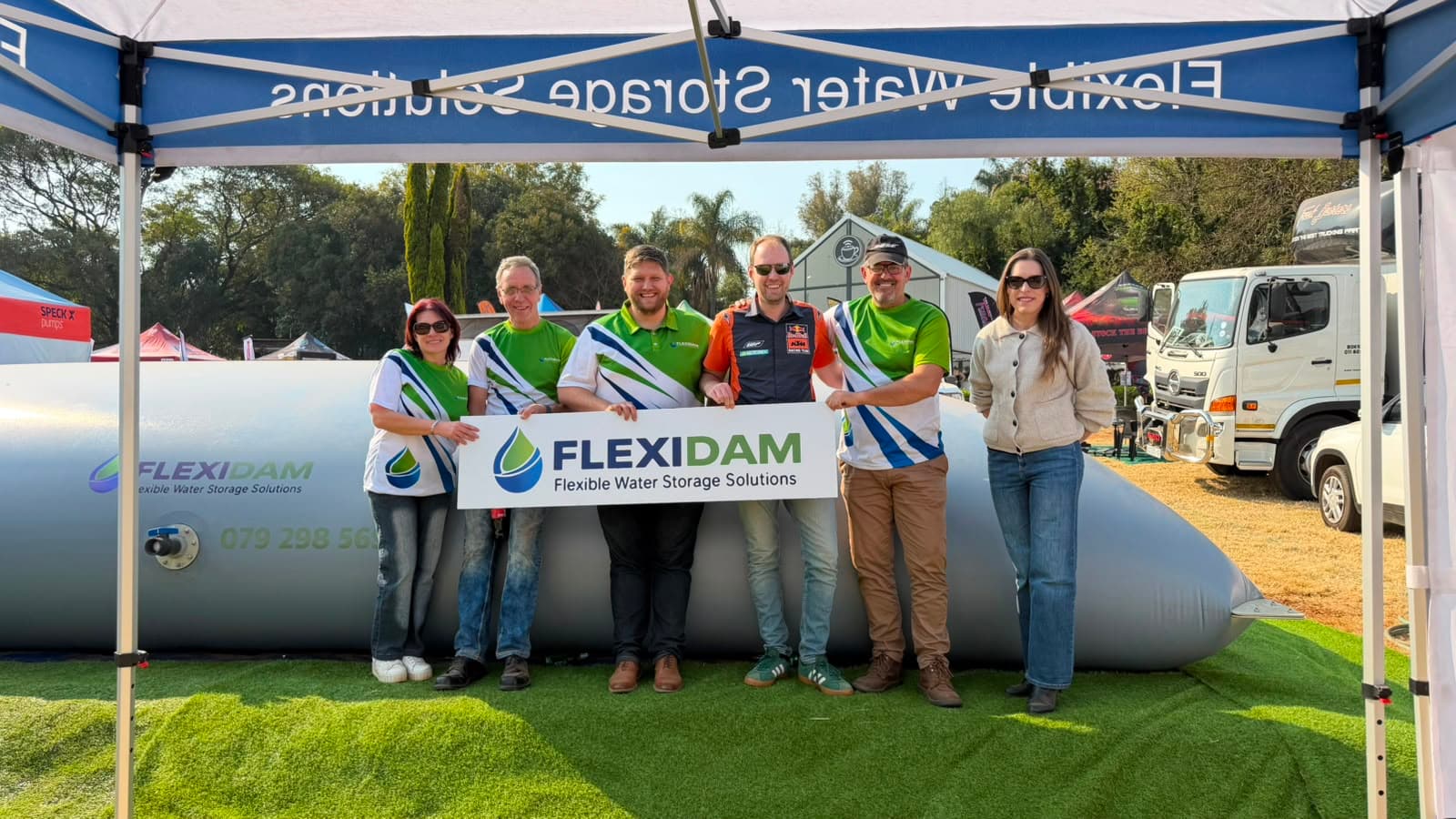 The FlexiDam team in front of a filled flexible water tank fabricated from PVC liner, on the stand at KragDag 2026